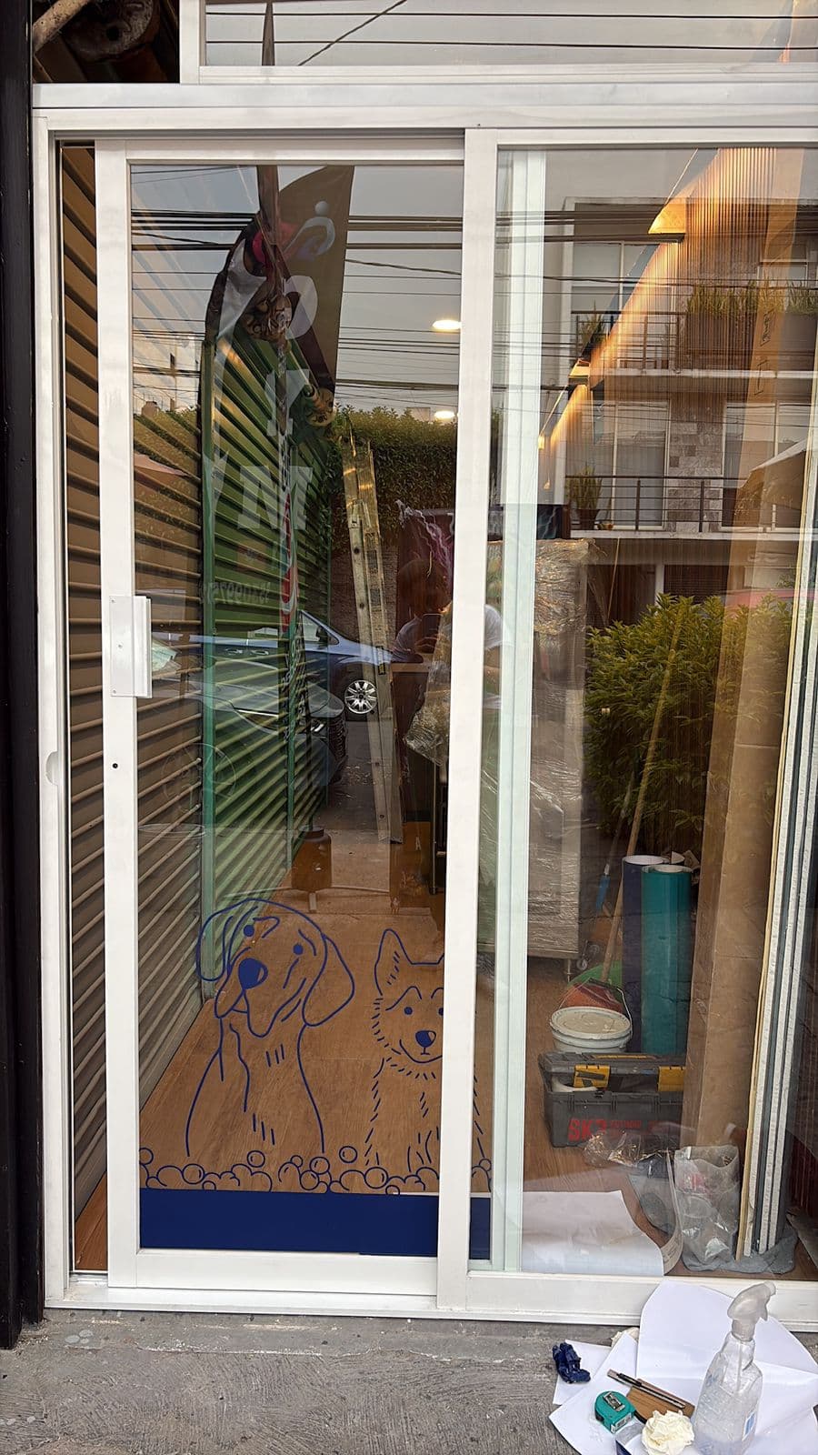 Puerta corrediza de vidrio con marcos blancos y dibujos lineales azules de dos perros.